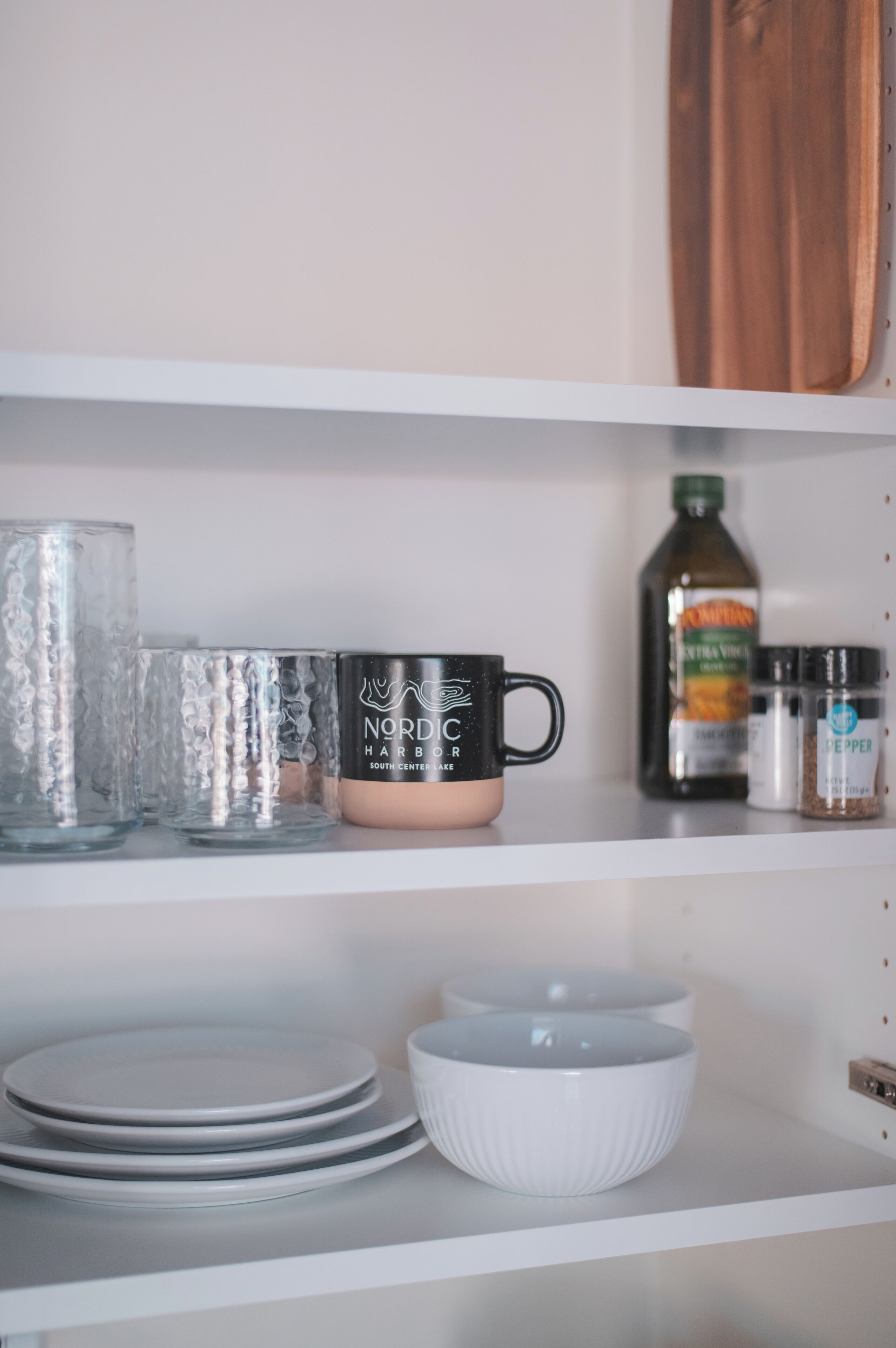 Une étagère contenant des ustensiles de cuisine, notamment de la vaisselle, une tasse à café et des bouteilles de condiments.