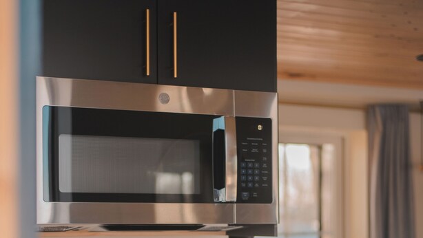 Een kleine keuken met een magnetron, een spoelbak en een klein aanrecht.