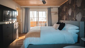 Een slaapkamer met een bed, een plafondventilator, een televisie en uitzicht op de omgeving.