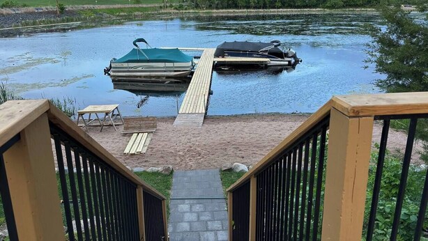 A dock with two boats, a wooden deck, and a small outdoor seating area. - Nordic Harbor | Room 5 | Cedar Shadows (Center City)