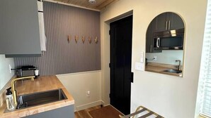 A compact kitchen with a wooden ceiling, a built-in sink, and a microwave. - Nordic Harbor | Room 5 | Cedar Shadows (Center City)
