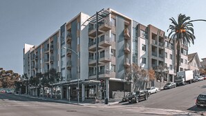 A multi-story building with balconies, a covered entrance, and a palm tree in the background. - Beautiful Downtown San Diego Studio (San Diego)