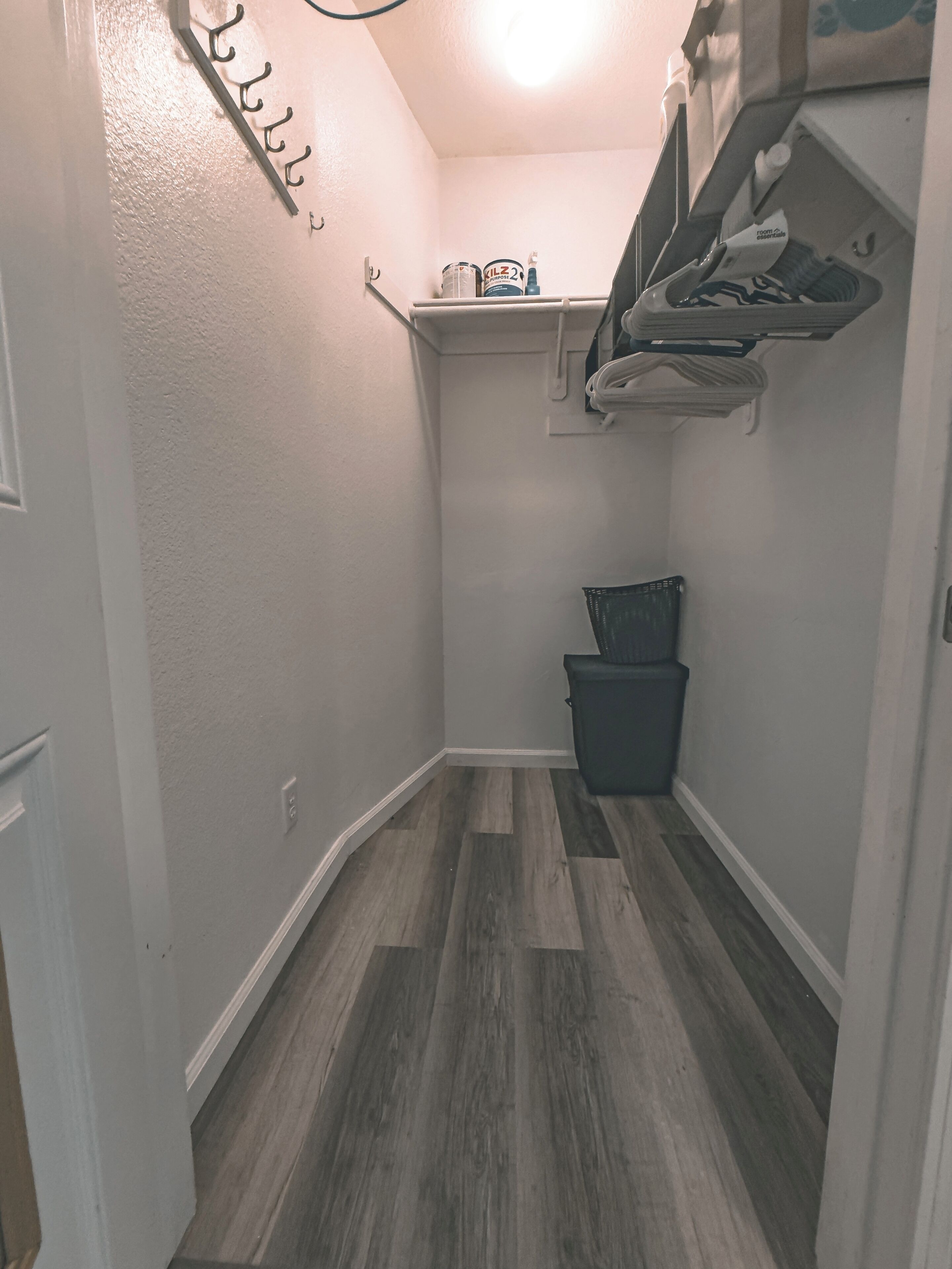 A narrow hallway with a wooden floor, a trash bin, and a ceiling fan.