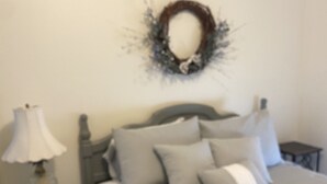 Une chambre à coucher avec un lit, des tables de chevet, une lampe et un élément de décoration murale.