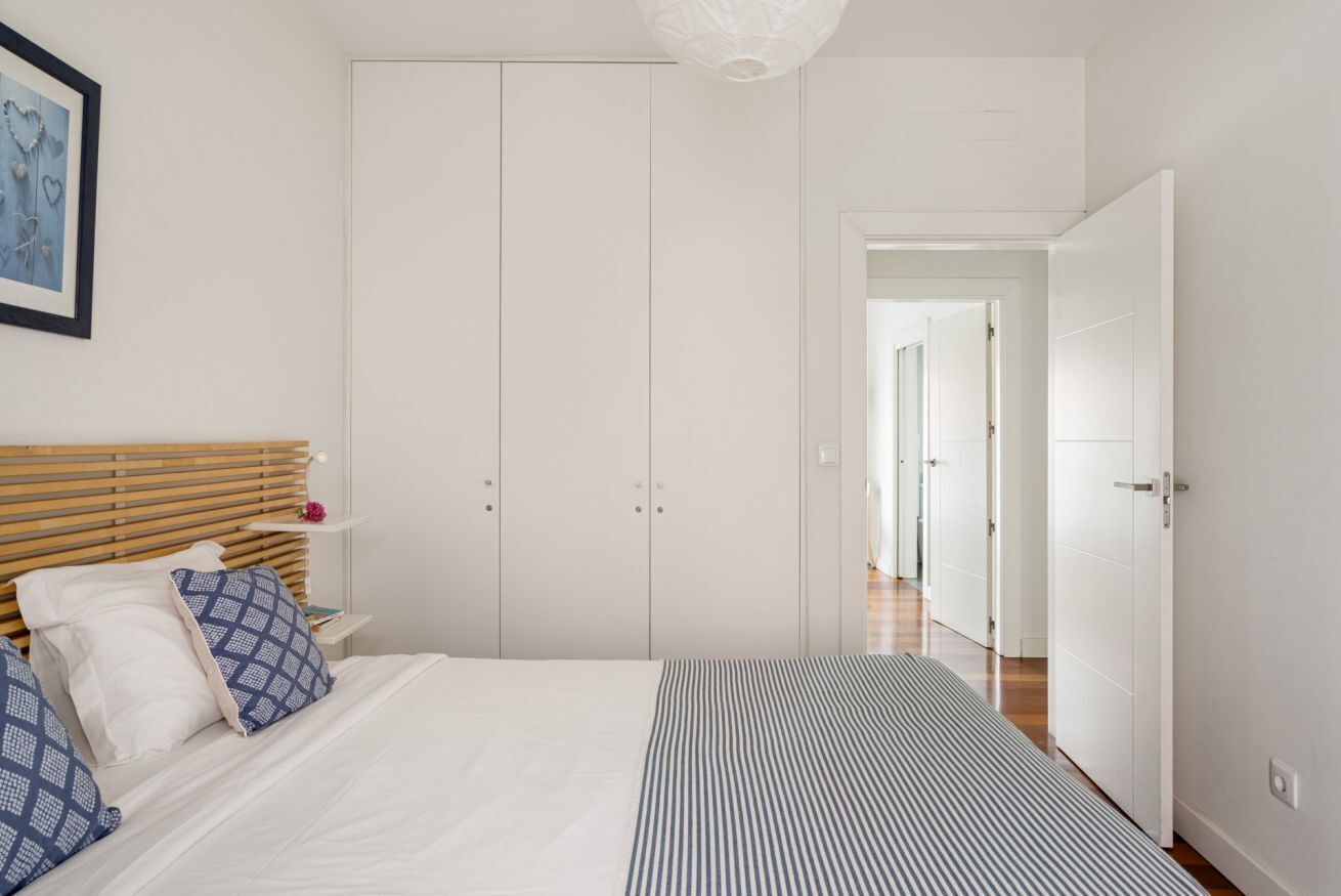 Un dormitorio con cama, armario, mesita de noche y un cuadro en la pared.