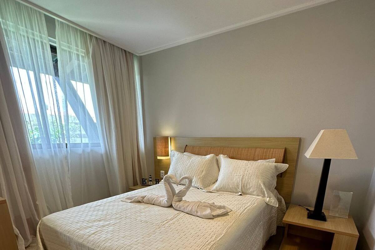 A neatly made bed with a quilted cover, a wooden headboard, and two bedside lamps.