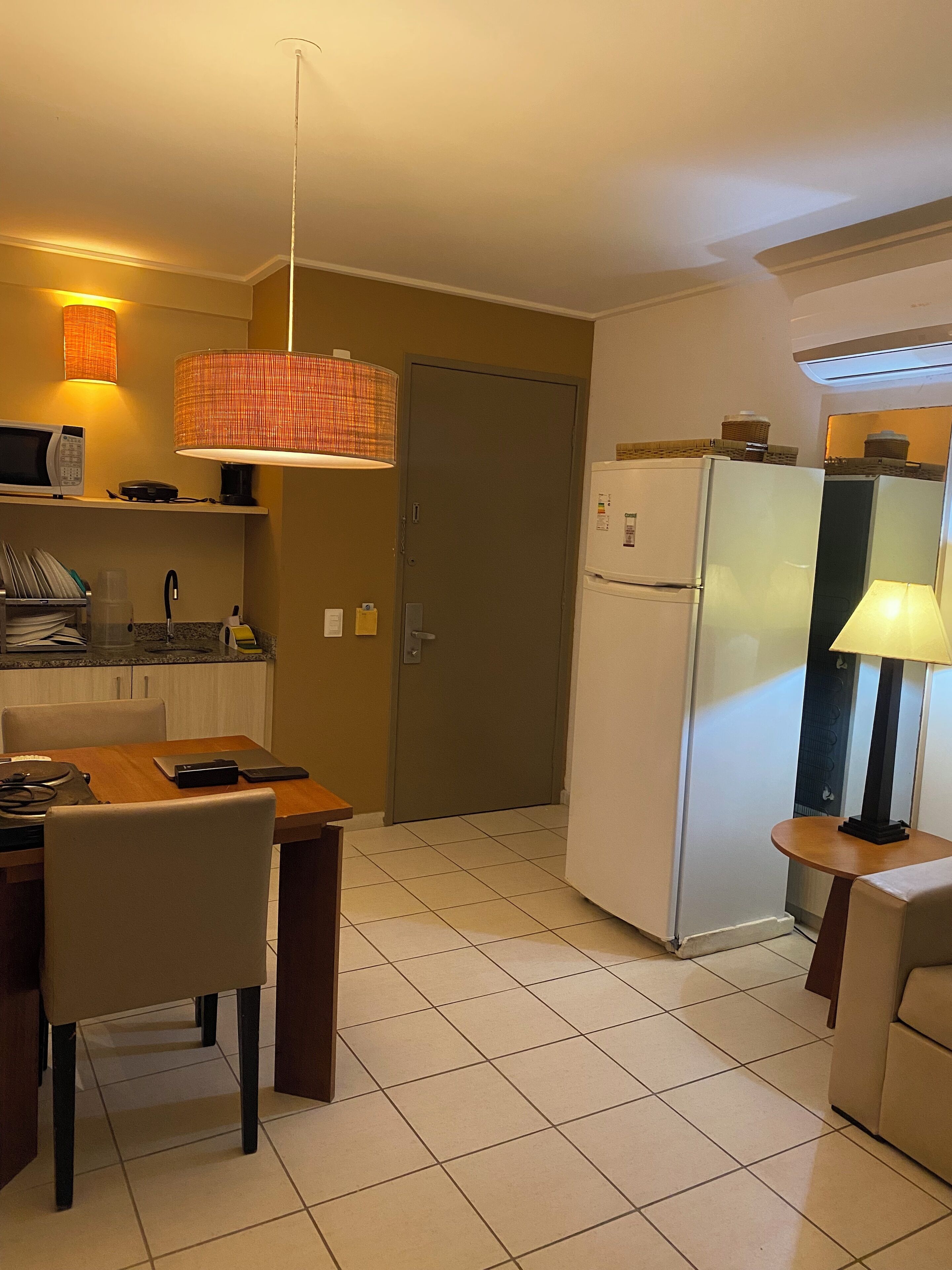 A compact kitchen with a microwave, refrigerator, and a dining area with a table and chairs.