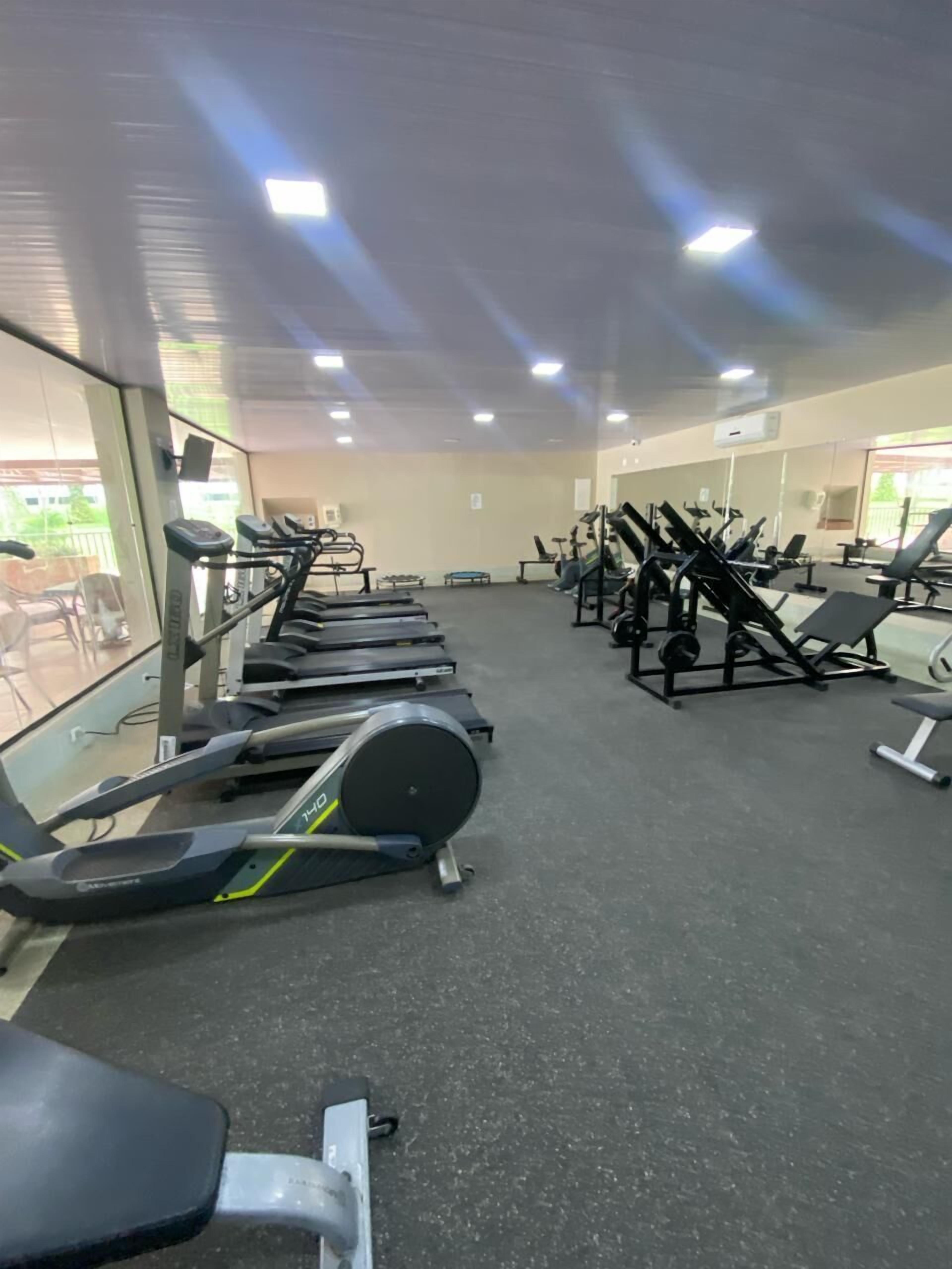 Uma academia equipada com esteiras, bicicletas ergométricas e aparelhos de musculação.