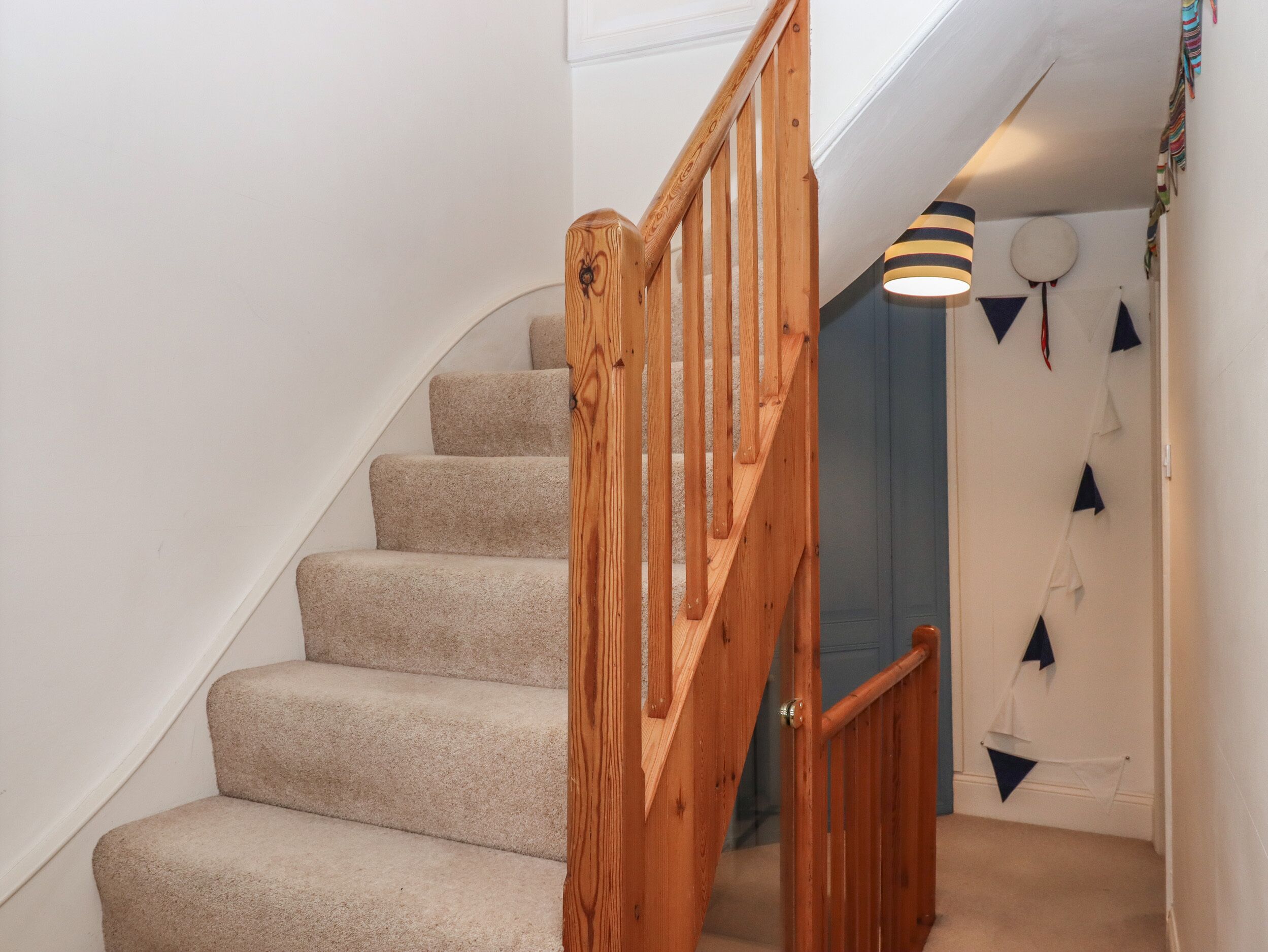 A staircase with wooden railings and beige carpeted steps leading to a landing.