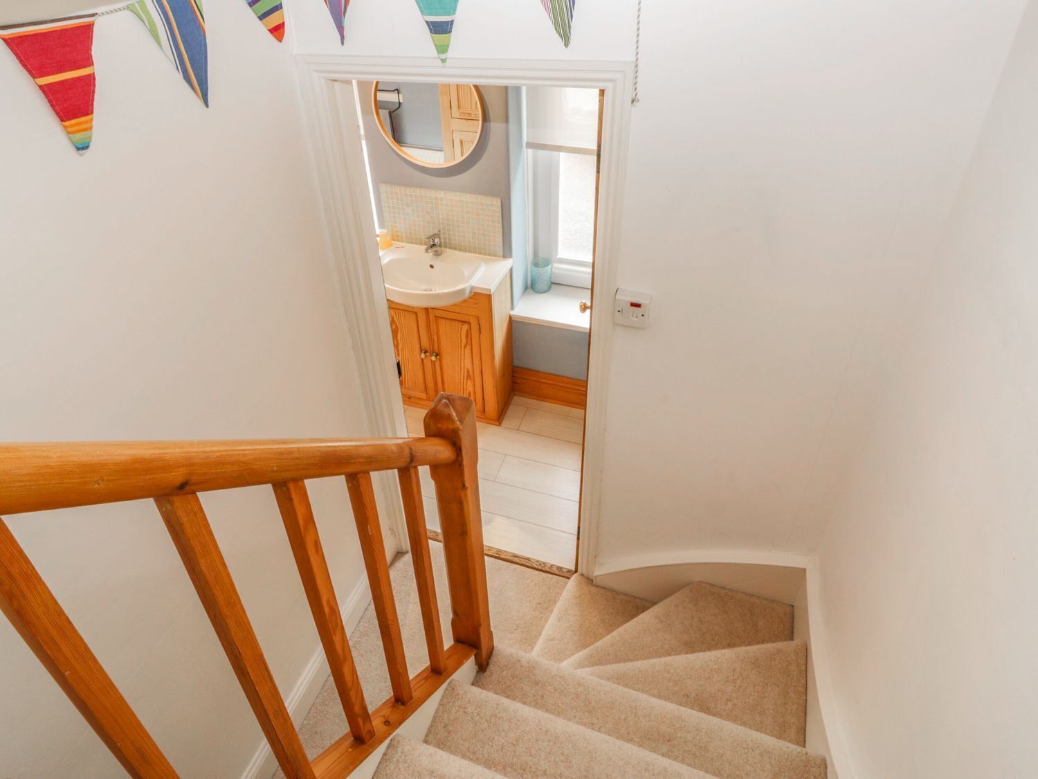 A wooden staircase leading to a bathroom with a sink and mirror.