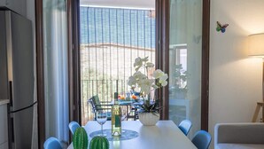 A dining area with a table, chairs, a vase with flowers, a bottle, and a cactus. - Residenza Le Terrazze - Affitti Brevi Italia (Valledoria)