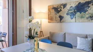 A room with a dining table, a vase with flowers, a world map on the wall, a lamp, and a sofa. - Residenza Le Terrazze - Affitti Brevi Italia (Valledoria)