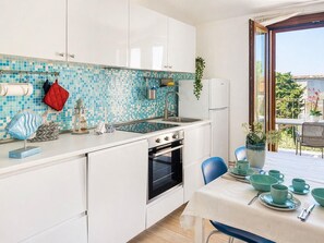 A modern kitchen with white cabinets, a blue mosaic backsplash, and a dining area with a table set for four.
