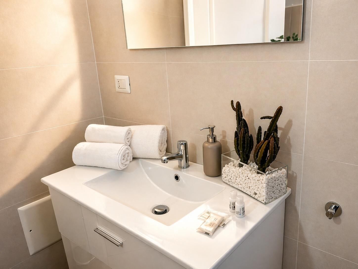 A bathroom with a white sink, a mirror, a towel rack, and a cactus plant.