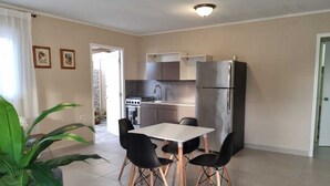 A compact kitchen with modern appliances, a dining area with four chairs, and a large potted plant. - Taminaka Comfortable III (Oranjestad)