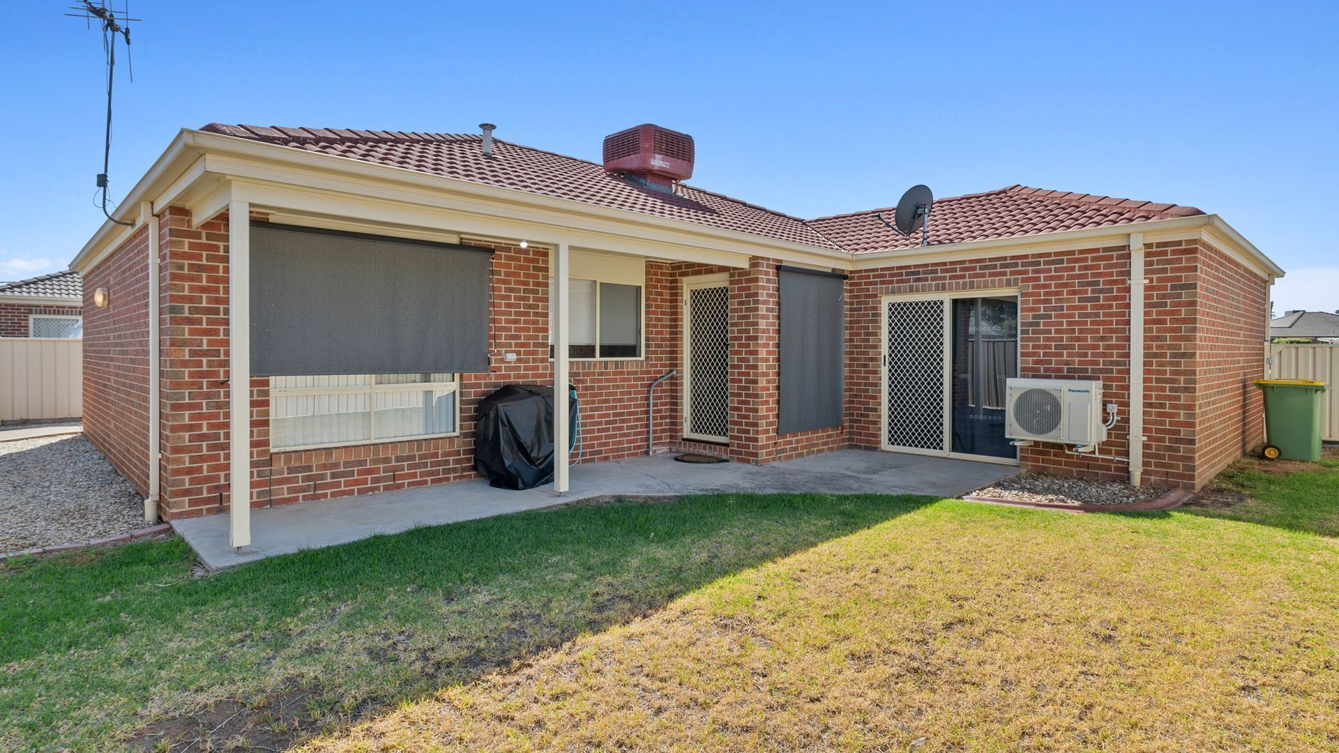 A single-story brick house with a covered patio, a sliding glass door, and an air conditioning unit.