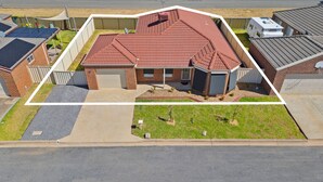 Une maison d’habitation avec un toit recouvert de tuiles rouges, une façade en briques et un garage.