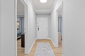A hallway with a white door, wooden flooring, and a patterned rug. - 3 Bedroom 3 Bathroom Reunion 7658 (Four Corners)
