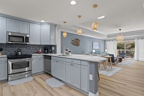 A modern kitchen with stainless steel appliances, grey cabinetry, and a central island.