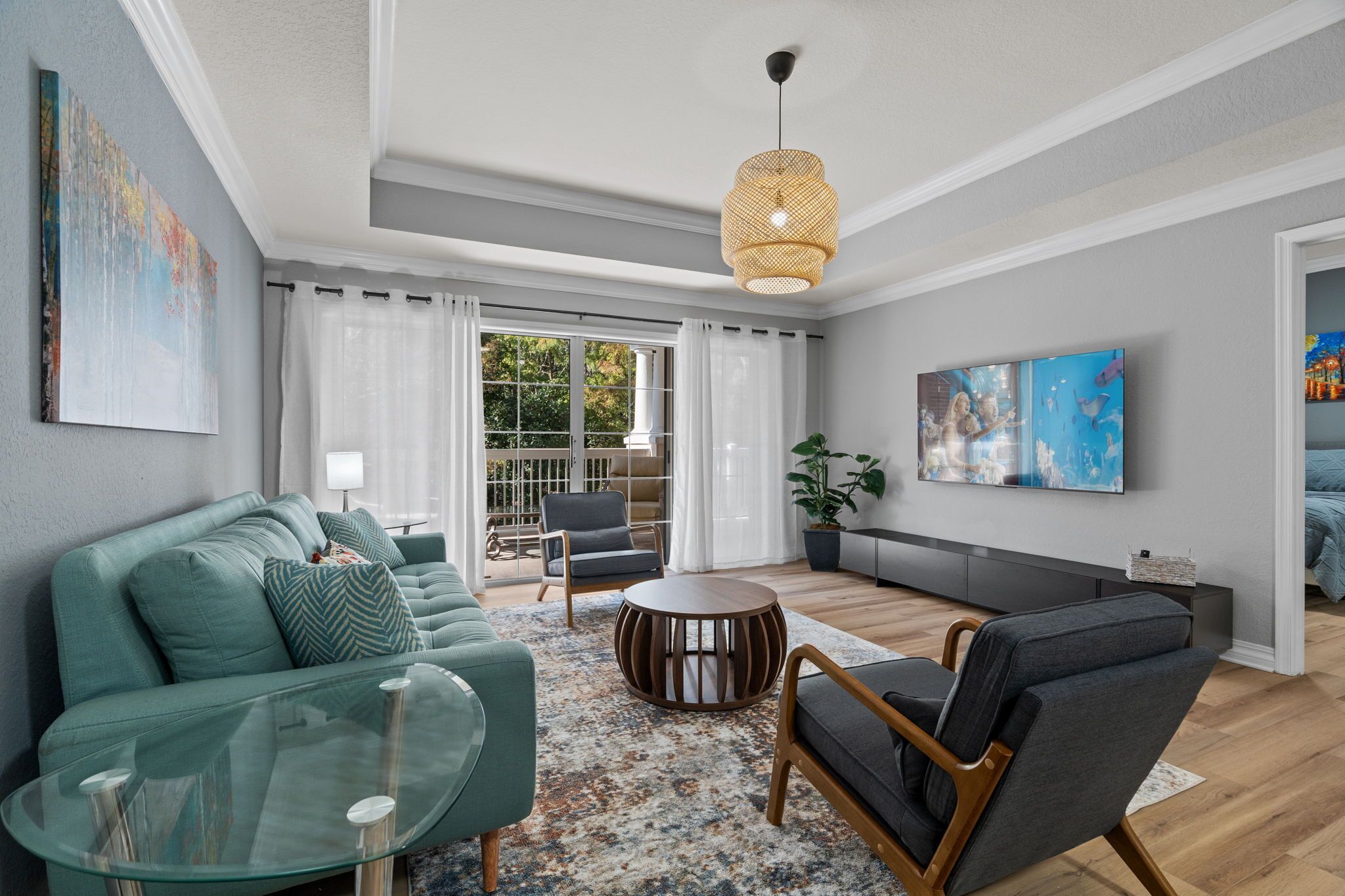 A modern living room with a sofa, armchair, coffee table, and a TV mounted on the wall.