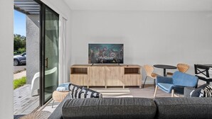 A modern living room with a large flat-screen TV, a wooden entertainment unit, and comfortable seating.