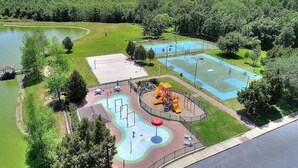 A park with a basketball court, playground, and a small pond.