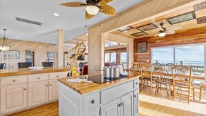 Una cocina amplia con armarios de madera, una isla central y un comedor con sillas de madera.
