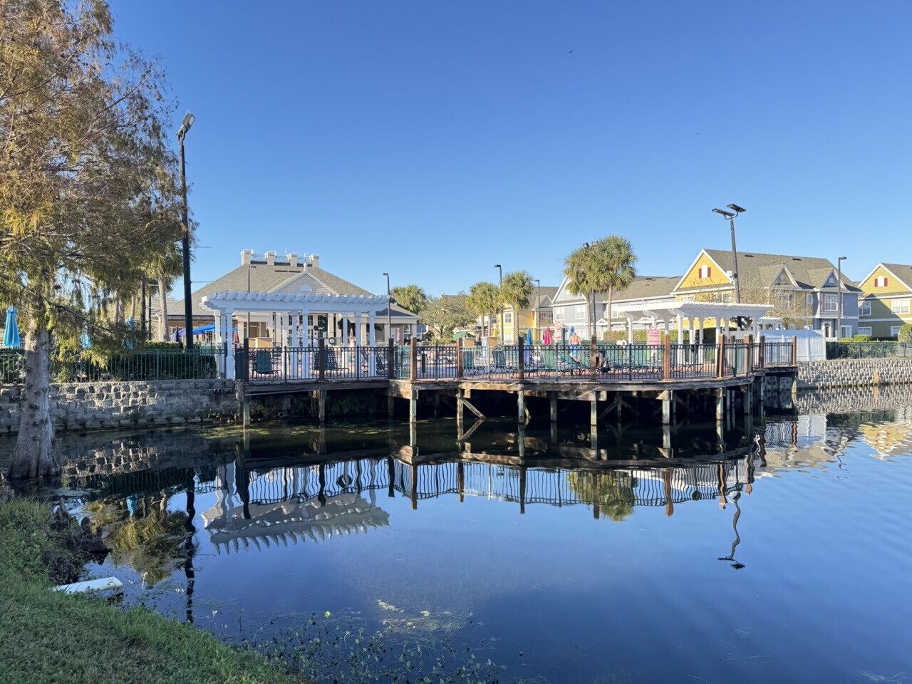 A waterfront property with a dock, a small bridge, and a reflection in the water.