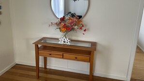 Ett konsolbord i trä med en glasskiva, ett dekorativt föremål i form av en stjärna och en vas med blommor.