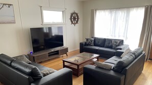 Ett modernt vardagsrum med en platt-TV, två soffor, ett soffbord och en dekorativ skeppsratt.