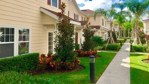 A row of townhouses with a well-maintained lawn, a sidewalk, and mature trees.