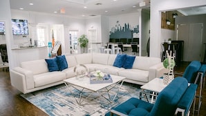 A modern living room with a white sectional sofa, blue accent pillows, a coffee table, and blue armchairs.