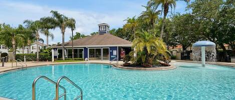 Una piscina con una palmera y una estructura cubierta al fondo.