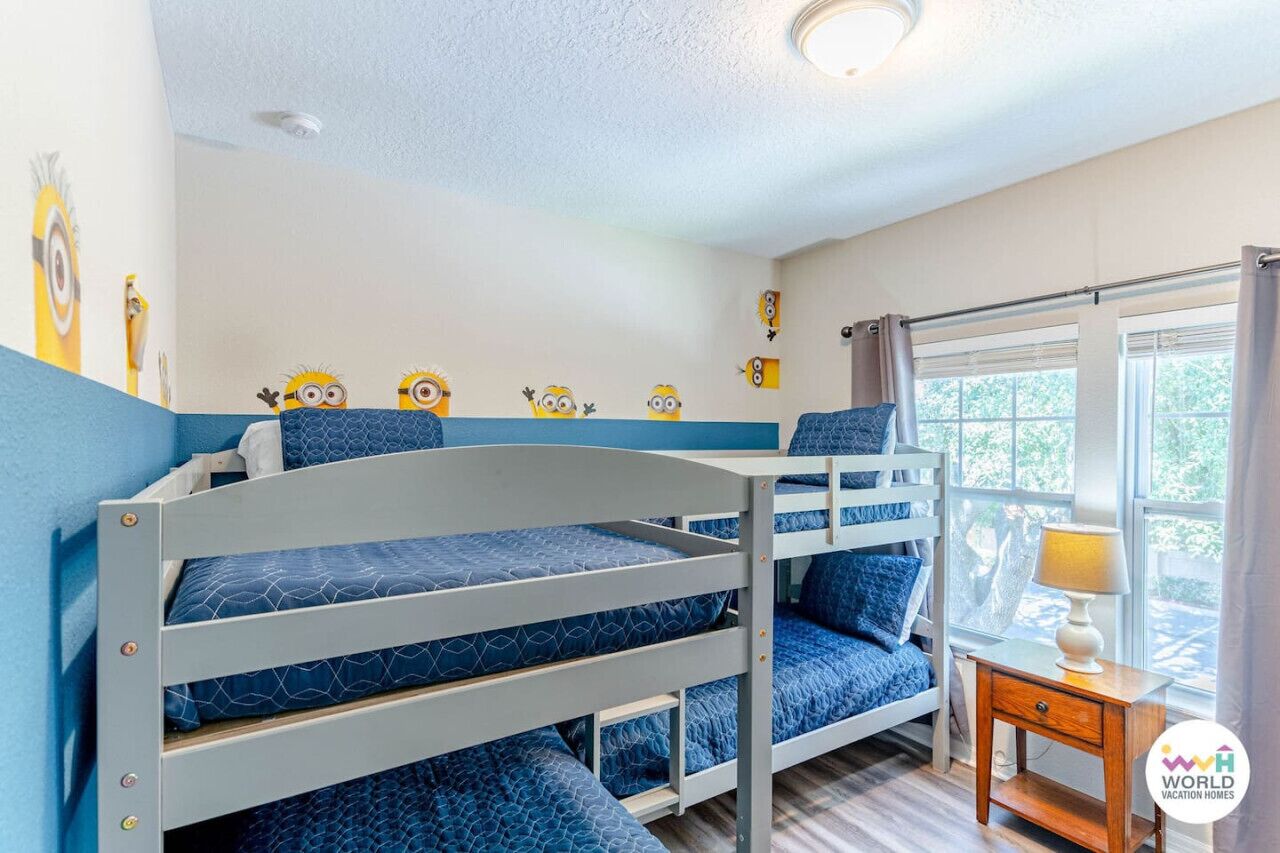 Ett rum med en våningssäng, ett fönster, en lampa och väggdekorationer med Minion-motiv.