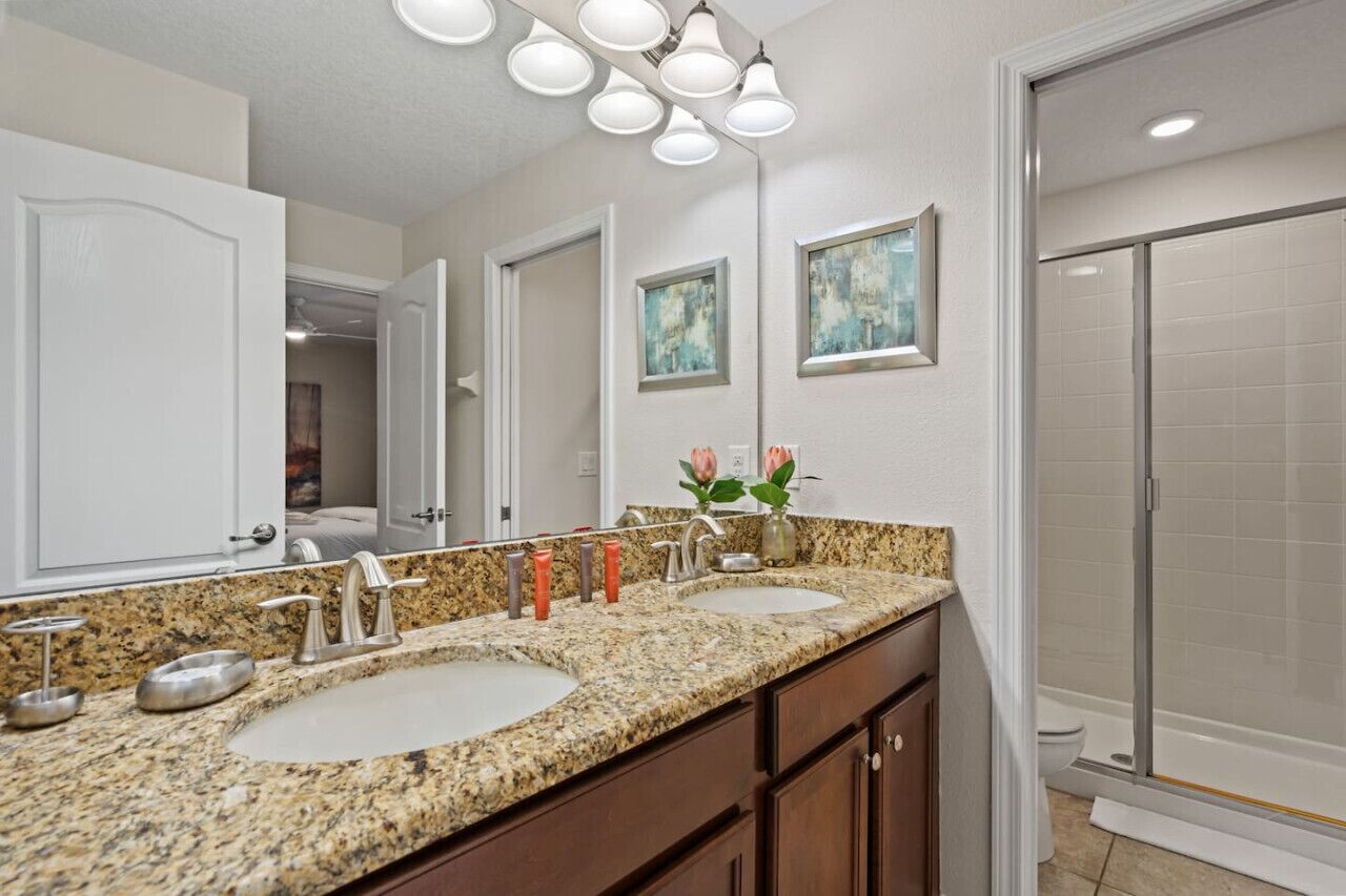 A bathroom with two sinks, a large mirror, and a shower.