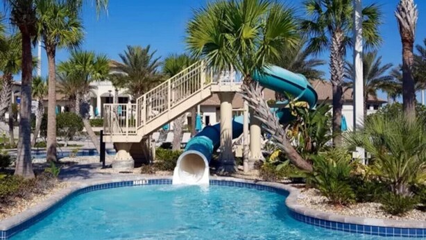 Ein Pool mit Wasserrutsche, Palmen und einem Gebäude mit Balkon.