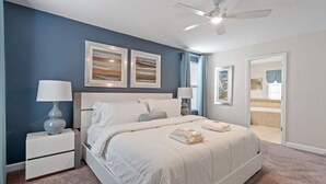 Ein Schlafzimmer mit einem Bett, Nachttischen, einem Deckenventilator und Kunstwerken an den Wänden.