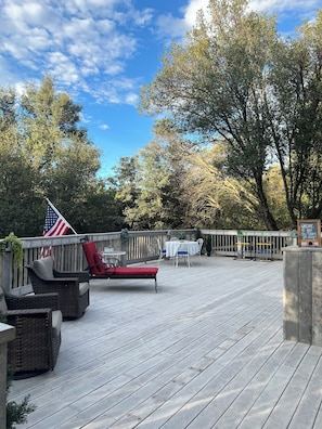 A deck with outdoor furniture, an American flag, and a welcome sign.