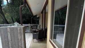 Ein überdachter Außenbereich mit Betonboden, einer Holzterrasse und einem Fenster mit Blick auf die Terrasse.