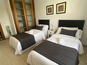 Two single beds with black and white bedspreads, each with matching pillows, are positioned side by side.