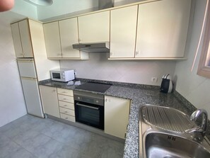 Compact kitchen with a minimalist design, featuring a stainless steel sink, oven, and ample counter space.