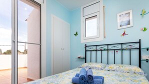 A bedroom with a bed, a window, a wardrobe, and a small shelf.