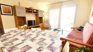 Una sala de estar acogedora con una mesa redonda, un sofá y un televisor.