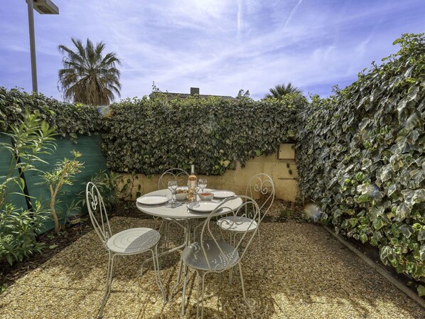 Enjoy meals al fresco at this outdoor dining area, surrounded by lush greenery and a majestic palm tree.