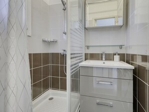 Enjoy a refreshing shower in this sleek bathroom with a glass-enclosed shower area and modern amenities.