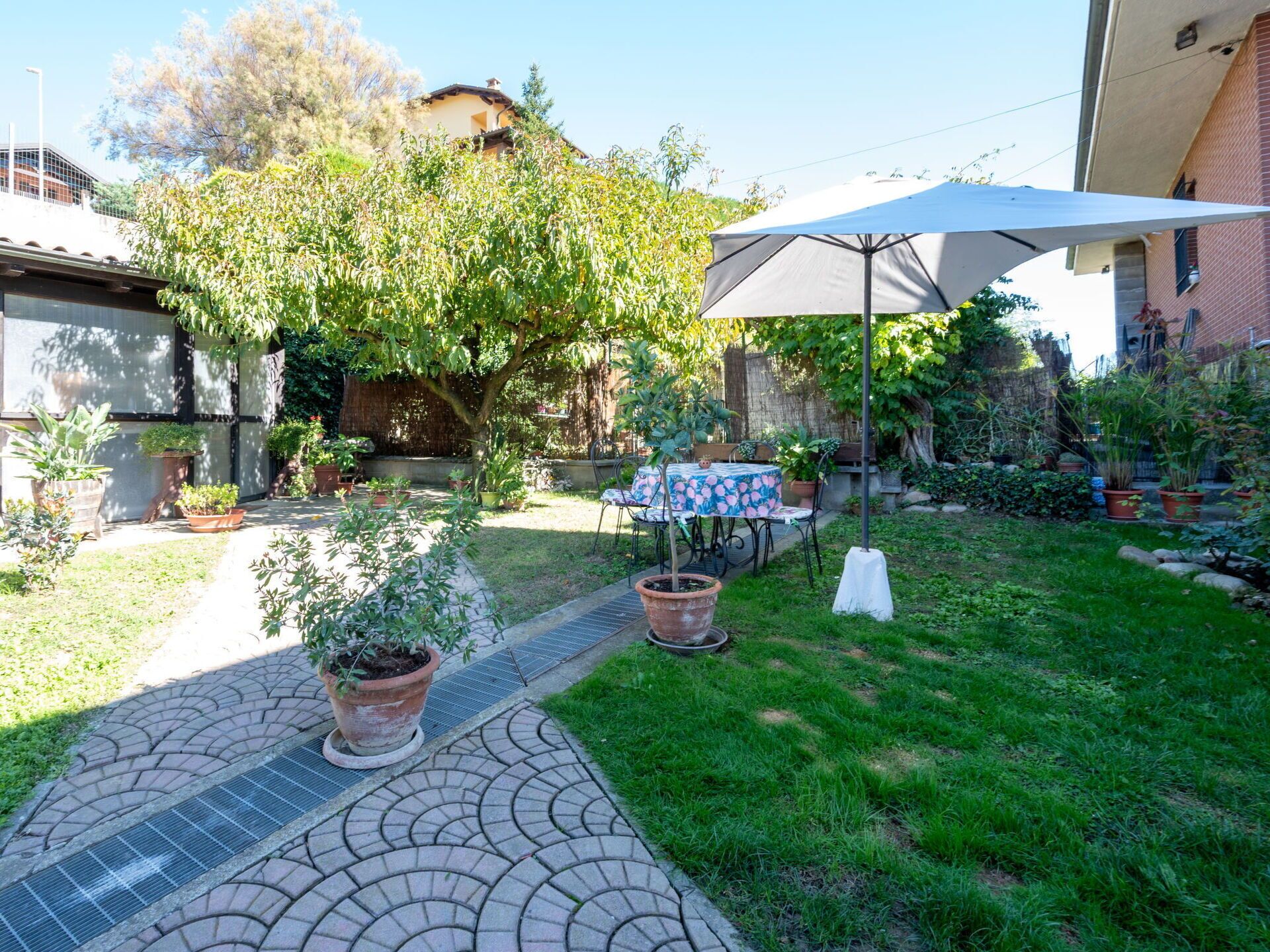 A patio area with a table and chairs, surrounded by potted plants and a large umbrella.