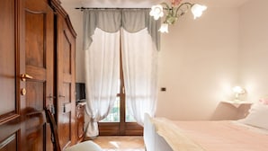 A bedroom with a bed, a wooden wardrobe, a chair, a desk with a lamp, and a window with curtains. - Beautiful private villa for 4 people with A/C, private pool, WIFI, TV, patio and pets allowed (Montaldo Scarampi)