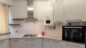 A modern kitchen with white cabinets, a gas stove, a built-in oven, and a stainless steel range hood. - Nice apartment for 4 people with WIFI, TV and balcony (Dumenza)