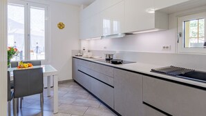 A modern kitchen with white cabinets, a black countertop, and a window with a view of buildings. - Lovely apartment for 4 guests with A/C, WIFI, patio and pets allowed (Bellano)