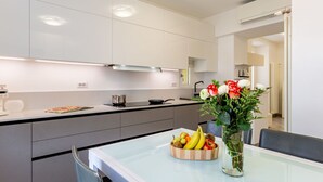 A modern kitchen with white cabinets, a glass-top dining table, and a fruit bowl. - Lovely apartment for 4 guests with A/C, WIFI, patio and pets allowed (Bellano)